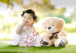 Baby Sitting on Green Grass Beside Bear Plush Toy 5K