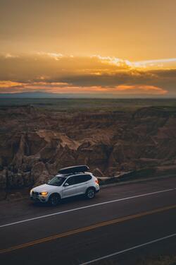BMW Car on Side of Road Near Mountain Terrain During Sunset