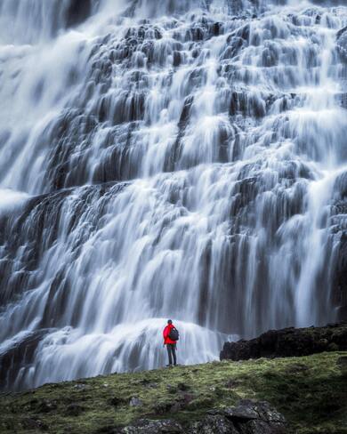 Man Standing in Front of Big Waterfall