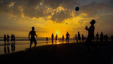 People Play on Beach During Sunset