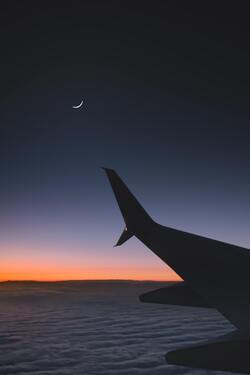 Airplane Flying Over The Clouds During Sunset