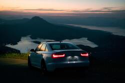 Audi Car Near Mountains With Pond Under Sky at Sunset