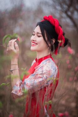 Girl With Cute Smile in Red Dress Looking to Flower
