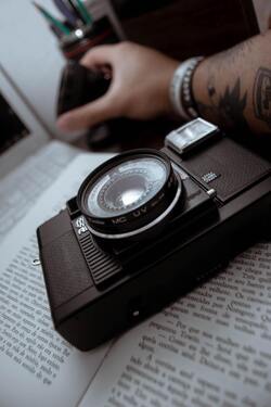 Male Photographer Sitting at Table With Camera And Book